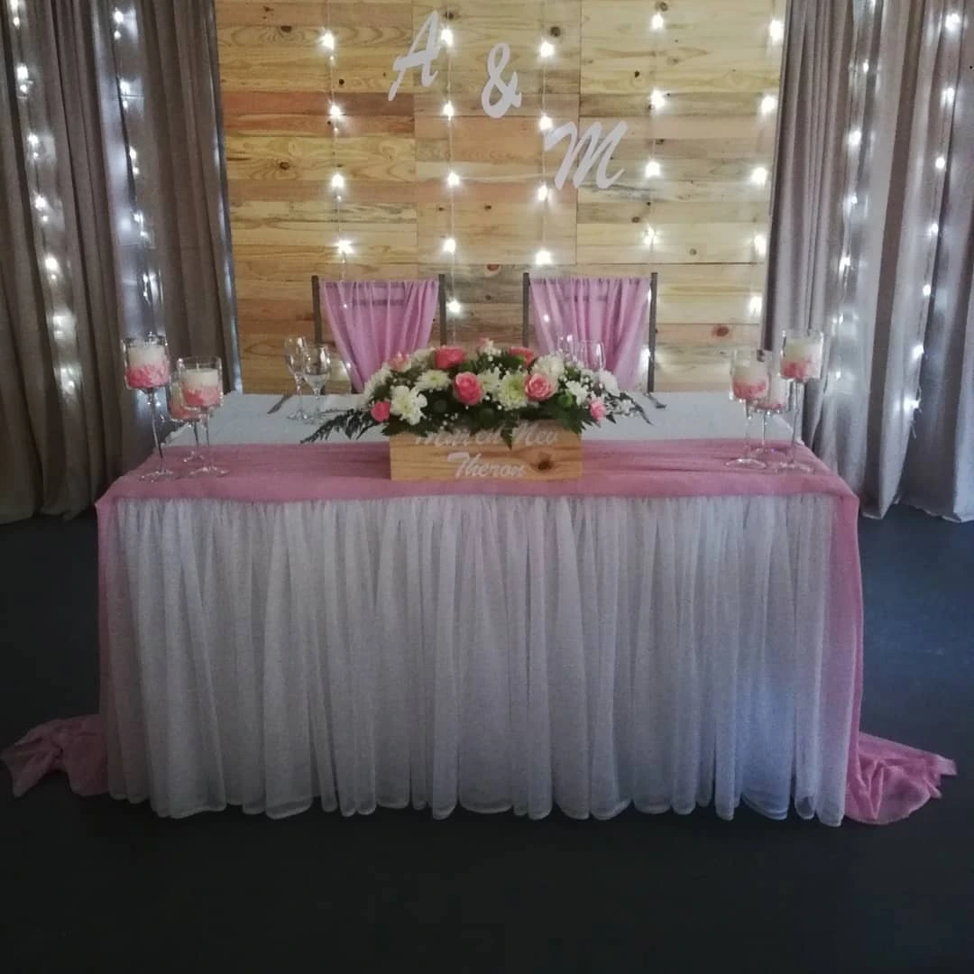 Fairy-lit wedding sweetheart table with wooden backdrop